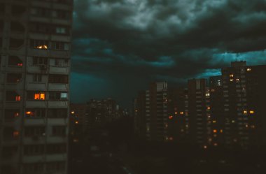 Karanlık mavi fırtınalı gece bulutlu gökyüzünün altında çok katlı apartmanlar olan bir gece şehri. Pencerelerde ışıklar yanıyordu. Yatak odası uykulu topluluk