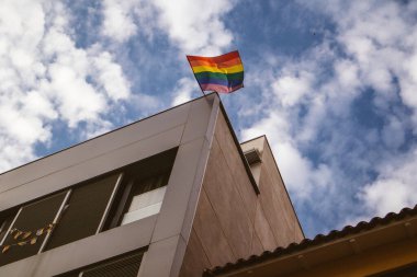 Gökyüzüne karşı modern bir binanın köşesinde çok renkli bir LGBT bayrağı. Çeşitlilik, eşcinsel azınlık, gurur ayı sembolü. Lezbiyenler, eşcinseller topluluğu. Gurur ayı. 