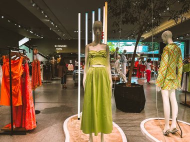 Madrid, İspanya. 1 Haziran 2024. Manikinlerin elbise giydiği modern bir kadın moda mağazasının içi. İspanyol pazarı içeriden. Dişi yeşil elbise. 