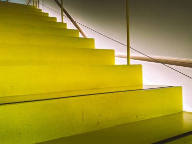 Yukarıdaki boş, parlak, sarı merdivenlere bakıyordum. Bir ofis binasının altından yukarı bakıyordum. Çağdaş mimari tasarım. Merdivenler kapalı.