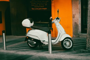 Madrid, İspanya. 11 Temmuz 2024 'te turuncu bina cephesinin yakınındaki eski bir şehir sokağına beyaz bir scooter park etti. Ekolojik şehir ulaşımı. Modern motosiklet.