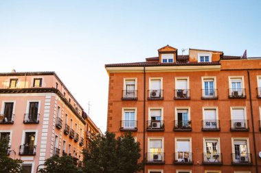 Tipik turuncu ve pembe bina pencereleri. Mimarlık tarzları mavi gökyüzüne karşı. Apartman kırmızı tuğla binalar şehir merkezindeki ön cephe manzarası.