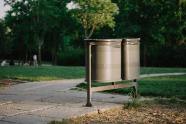 Plastik çöp kutusu. Yaz günü şehir parkında metal siyah çöp tenekeleri. Çevreye özen, temizlik, ekoloji konsepti. Gündüz vakti Parkland.