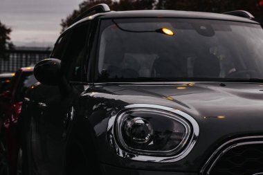 Farı ve kaputu parlak dış görünüşlü siyah bir araba. Modern otomobilin siyah anahtarı. Arabalar akşam caddesine park edildi.. 