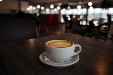 Varşova, Polonya 1 Şubat 2022 beyaz porselen kapuçino fincanı. Kahverengi köpüklü, tabakta, nefis bir sabah içeceği. 