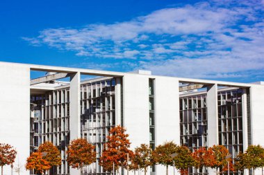 Berlin, Almanya. 2 Ekim 2022 Paul Lobe Haus mavi gökyüzüne karşı. Turuncu yapraklı ağaçlar şehir caddesinde bir sırada yetişiyor. Modern şehir mimarisi.