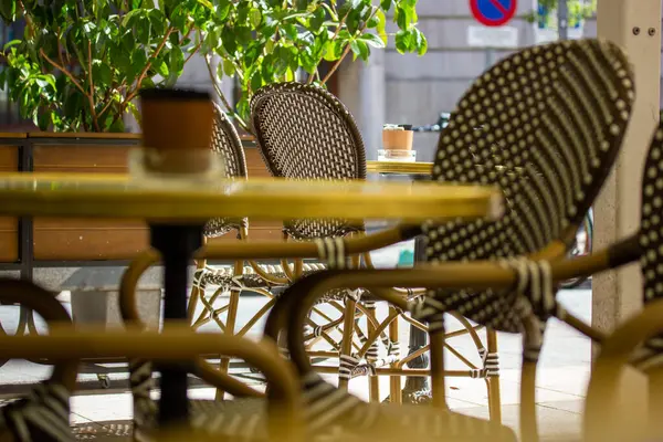 Yaz günü boş eski moda kafe restoranı terası. Sandalyeler ve yuvarlak ahşap masa. Şehir uzayındaki hasır bahçe mobilyaları. Tatillerde dinlenmek için güzel bir yer. Seçici odak.