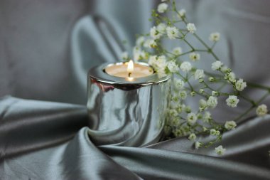 Beyaz, taze çiçek açan kaplıca hayatı, ipek gri arka planda yanan metalik mum. Düğün aksesuarları, çiçek aranjmanı, buketten filizlenen çiçek. Evde dinleniyorum..