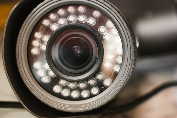 Close-up front view of a surveillance camera lens. An electronic tool. Video recorder. CCTV cameras, surveillance, monitoring, control and protection, guard of private territory, home, office. 