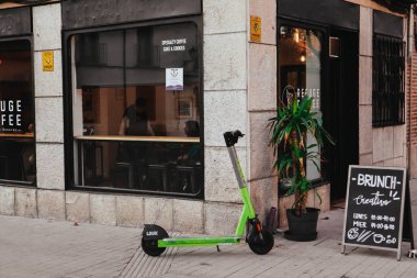 Madrid, İspanya. 1 Şubat 2024 Kafe cephesi şehir caddesinde, yeşil scooter kaldırıma park edilmiş. Şehir yaşam tarzı. Kafeteryada branç menüsü, kahve dükkanı.