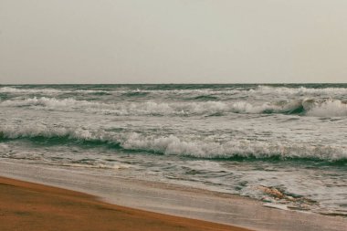 Yeşil dalgalar kıyıya vuruyor. Sakin doğal deniz manzarası. Güzel okyanus dalgaları. Dalgalı su ve kumlu plaj. Zümrüt sular. Sıvı soyut doku.