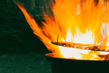 Alevler Brezilya 'da yanıyor. Geceleri açık havada barbekü. Tehlikeli sıcak turuncu alevler. Doğanın enerjisi. Alevli hareket. Metal barbekü ızgarası.