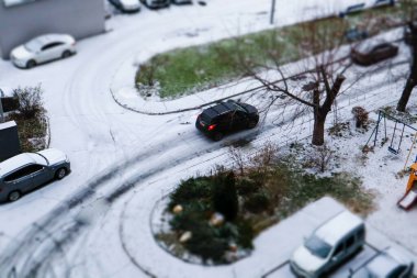 Kyiv, Ukrayna 'da 7 Aralık 2024' te avlunun tepesinden aşağı bakan yol ve arabaların kış günü park edildiği yer. Karla kaplı bir yol Bir araba caddede ilerliyor