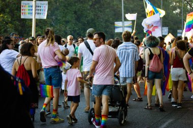 Madrid, İspanya, 1 Temmuz 2022 Yeni doğmuş bebekli eşcinsel aile, Gurur Ayı 'ndaki çocuklar. Gökkuşağı çoraplı genç bir baba bebek arabasıyla Modern insan yaşam tarzı