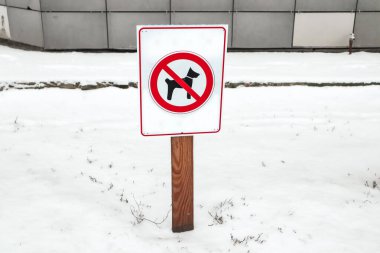 Kışın şehir caddesinde köpek yürümesini yasaklayan kırmızı resimli beyaz ahşap uyarı levhası. Bahçede köpeklerin dolaşması yasak.
