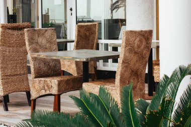 Restoran veya otel kafesinin terasında Rattan bahçe mobilyaları. Doğal malzemelerden yapılmış dış mobilyalar. Gün içinde kafeteryada boş oturuyor..