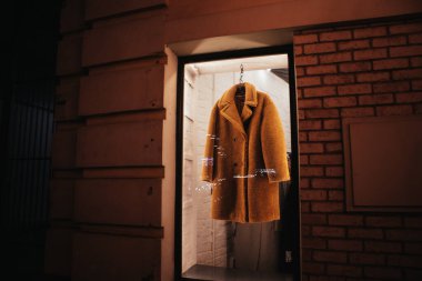 Geceleri kadın giyim mağazasının, mağazanın, mağazanın ve butiğin vitrininde kahverengi bir kürk askıya asılıyor. Moda konsepti.