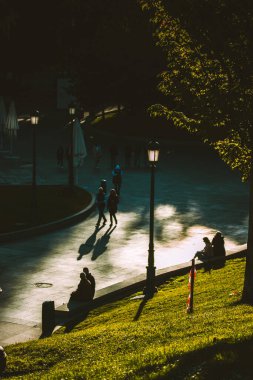 Madrid, İspanya. 1 Mayıs 2024 Baharda güneşli bir günde yeşil çimlerin üzerinde oturup rahatlayan insanlar. Şehir sakinleri güneşli bir günde burada. Dikey şehir fotoğrafı.