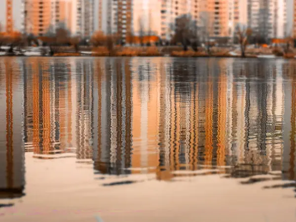 Yüksek çok katlı binaların sonbahar mevsiminde yansıdığı kentsel bir ortamda sakin su yüzeyi. Yüksek binalar. Sonbaharda şehir manzarası görünümü.