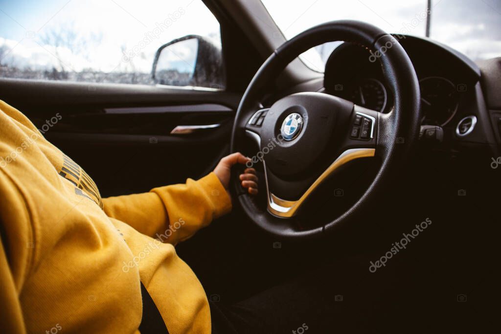 Kyiv, Ukraine May 1, 2022 Cropped photo of a faceless female driver inside BMW automobile holding the steering wheel. Travel by car. Comfort journey.