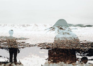 Okyanus kıyısındaki çakıl taşlı sahilde iki kişinin silueti. Yaratıcı çift pozlama fotoğrafı. Su ile eğlence. Doğayla uyum ve birlik. 