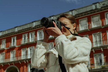 Madrid, İspanya. 27 Şubat 2024 Bir turist kadın İspanyol başkentini ziyaret ederken bir Plaza Mayor 'un fotoğrafını çekiyor. Gezgin fotoğrafçı. Eski kırmızı bina