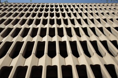 Modernist bir binanın ön cephesinde tekrar eden beton şekiller vardır. Tasarım, ışık ve gölgenin ilginç bir etkileşimini yaratır..