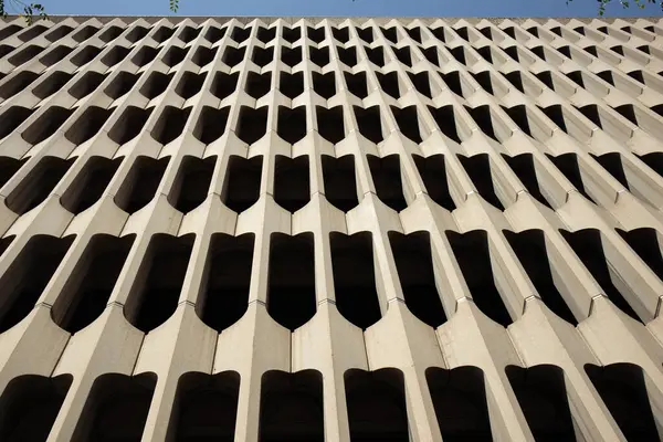 Modernist bir binanın ön cephesinde tekrar eden beton şekiller vardır. Tasarım, ışık ve gölgenin ilginç bir etkileşimini yaratır..