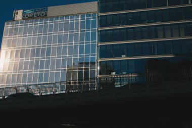 Madrid, İspanya 1 Mayıs 2022 mavi gökyüzü, iş yeri veya mimari temalı camdan pencereleri olan modern bir ofis binası. Kentsel alanda cam cephe.