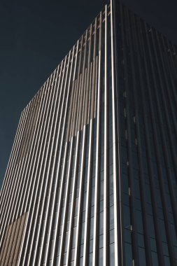 Etkileyici bir modern gökdelen açık mavi gökyüzüne uzanır, mimari hüner ve tasarım sergiler. Binanın ince çizgileri var. Şehir manzarası.