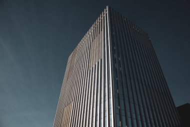 Etkileyici bir modern gökdelen açık mavi gökyüzüne uzanır, mimari hüner ve tasarım sergiler. Binanın ince çizgileri var. Şehir manzarası.