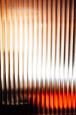 Dikey çizgileri ve bulanık ışığı olan soyut bir kompozisyon derinlik hissi yaratıyor. Renkler sıcaktan serin tonlara geçişi bulanık arkaplan