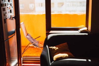 Rahat bir yaşam alanı güneş ışığıyla doludur. Yastıklı bir kanepe ve balkona açılan bir kapı ve dinlenmek için bir yer gösterilir. Salon terası..