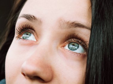 Yakın çekim bir kadının büyüleyici mavi gözlerinin büyüleyici güzelliğini yakalar. Karmaşık ayrıntılarını ve derinliklerini vurgular. Dua ederken yukarı bakıyor..