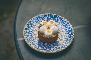 Üzerinde desenli mavi bir tabakta servis edilen ve karmaşık bir tasarım sunan bir pasta turtasının yukarıdan aşağı görüntüsü. Zarif tatlıda beyaz krema ve meyve dolgu var..