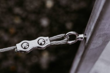 Güçlü metal bir kabloyu direğe bağlayıp güçlü bağlantılarını gösteren detaylı bir görüntü. Yağmurda açık havada parlak kablo bağlantısının yakın plan görüntüsü. 