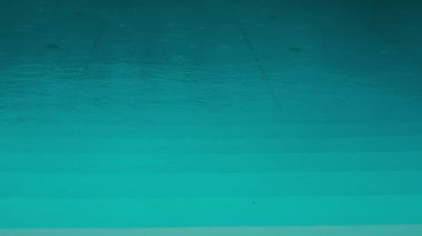 Güzel turkuaz mavi bir su ile sakin bir yüzme havuzu yağmur damlaları ile su yüzeyinde izler bırakır yağmurda dinlenmek için Spa alanı