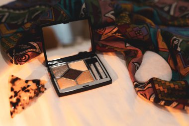 Bukovel, Ukrayna 8 Mayıs 2025 aynalı ve aplikatörlü lüks bir göz falı eşarp ve aksesuarların yanında duruyor. Kozmetikler.