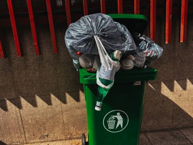 Madrid, İspanya 1 Mayıs 202 4A tam yeşil çöp tenekesi çöp torbalarıyla dolup taşan çeşitli atıklar, atık yönetimi ihtiyacını gösteriyor.