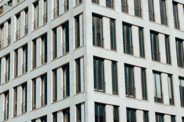Bir binanın ön cephesinin modern kentsel mimari görüntüsü, birbirinin tıpatıp aynısı çok sayıda dikdörtgen pencere ve balkon içeriyor ve minimalist bir tasarım sergiliyor..
