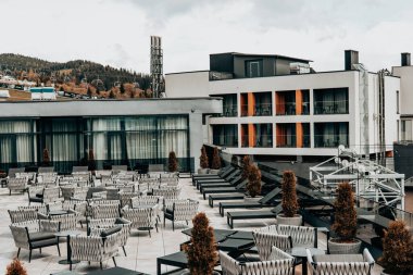 Bukovel, Ukrayna Modern çatı terasında sandalyeler ve masalarla dağlar ve kayak asansörleri manzarası sunuluyor. Açık hava oturma alanı. Rybas Oteli..
