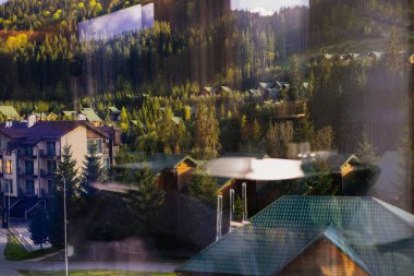 Bukovel, Ukrayna 1 Mayıs 2025 Gökyüzünün altında yemyeşil ağaçlar ve pansiyonlar olan güzel bir dağ manzarası. Manzaralı evler, tepelere kurulmuş pansiyonlar..
