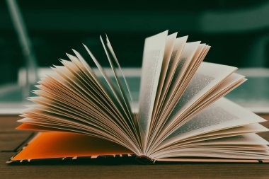 Kapalı sayfaları olan, derinlik ve bilgi içeren açık bir kitabın kapağı. Önplanda sayfalar olan açık bir kitap, okuma ve çalışmanın özünü bulanık arkaplanla yakalıyor..