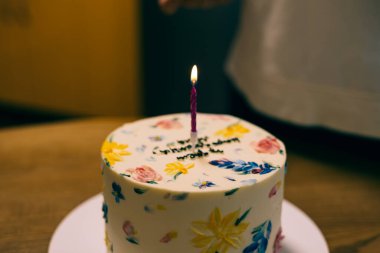 Çok güzel dekore edilmiş mum ışığında bir pasta, özel bir doğum günü kutlaması için mükemmel. Renkli çiçeklerle süslenmiş güzel bir pasta ve tek bir mum, kutlama için mükemmel..