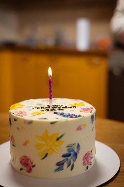 Çok güzel dekore edilmiş mum ışığında bir pasta, özel bir doğum günü kutlaması için mükemmel. Renkli çiçeklerle süslenmiş güzel bir pasta ve tek bir mum, kutlama için mükemmel..