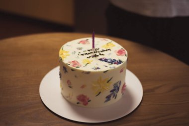 Çok güzel dekore edilmiş mum ışığında bir pasta, özel bir doğum günü kutlaması için mükemmel. Renkli çiçeklerle süslenmiş güzel bir pasta ve tek bir mum, kutlama için mükemmel..