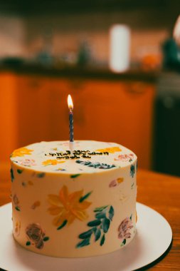 Çok güzel dekore edilmiş mum ışığında bir pasta, özel bir doğum günü kutlaması için mükemmel. Renkli çiçeklerle süslenmiş güzel bir pasta ve tek bir mum, kutlama için mükemmel..