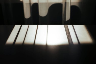 Yumuşak ışık perdenin içinden süzülerek gölgeler oyunu yaratır. Işık ve formun etkileşimi, bir sükunet hissi uyandırıyor. Ev sahnesi.