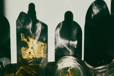 Tepeden çekilen bir çekim, yüzeyde soyut şekiller oluşturan cam nesneler tarafından oluşturulan bir ışık ve gölge oyunu yakalar. Bu mistik bir atmosfer ekler..