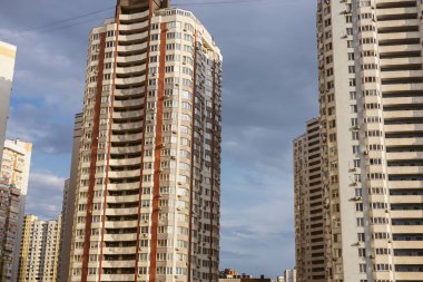 Kyiv, Ukrayna. 7 Haziran 2025 Bulutlu bir gökyüzüne karşı bir grup bina şehir manzarası yaratıyor. Gökyüzünün altında birçok penceresi olan uzun bir apartman. Arka planda başka binalar da görünüyor..